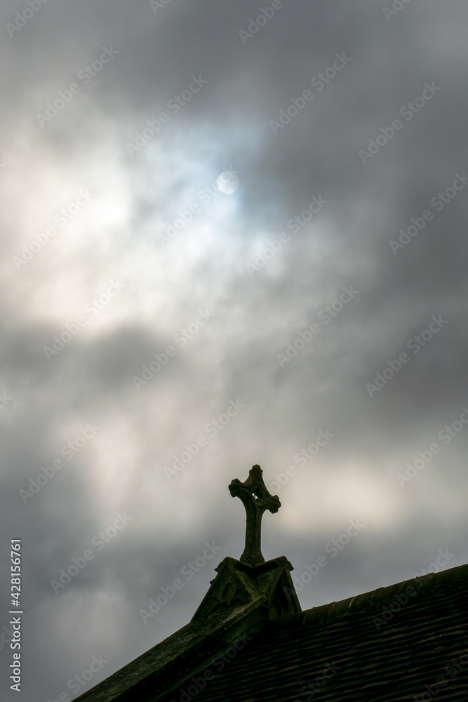 Fototapeta premium Religious Cross on ancient church building roof in cloud with pale sun