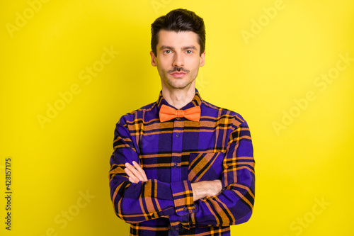Photo of young handsome positive smiling businessman with folded hands wear bow tie isolated on yellow color background