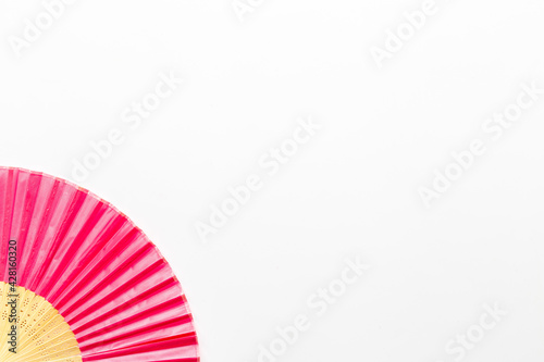 Pink open hand fan made of bamboo and paper. Top view