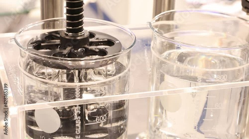 Laboratory mixer is stirring liquid in the glassware
