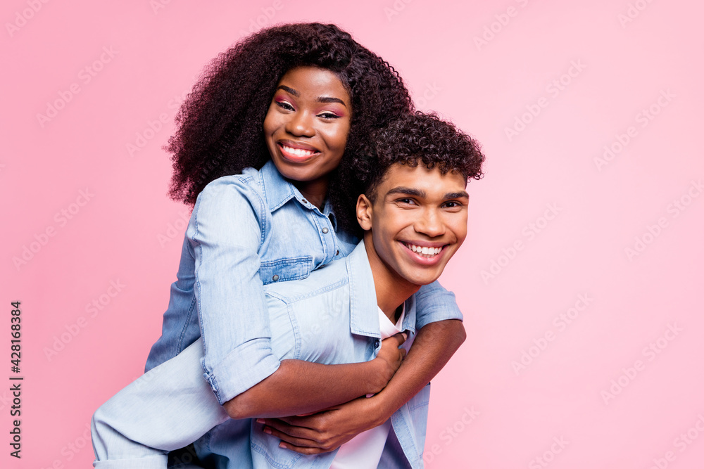 Photo of handsome dark skin guy piggyback attractive lady toothy smile isolated on pink color background Photo of handsome dark skin guy piggyback attractive lady toothy smile isolated on pink color background