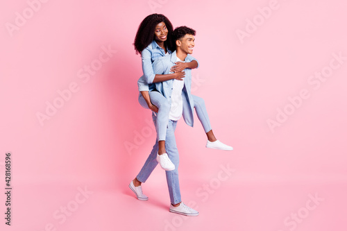 Full size profile photo of two dark skin persons guy piggyback lady look empty space isolated on pink color background