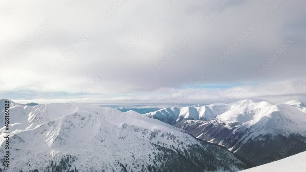 Picturesque view from a snowy landscape during the winter season. Mountains covered with snow against a beautiful cloudy sky in the city of Zakopane - Kasprowy Wierch