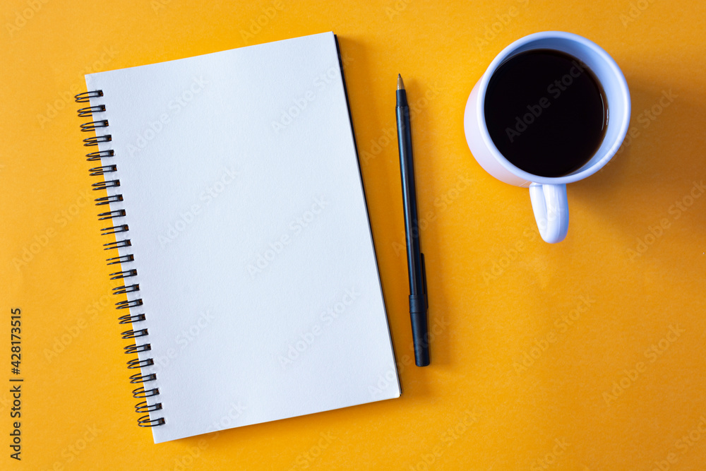 Notepad with pen and a cup of coffee on yellow background Notepad with pen and a cup of coffee on yellow background