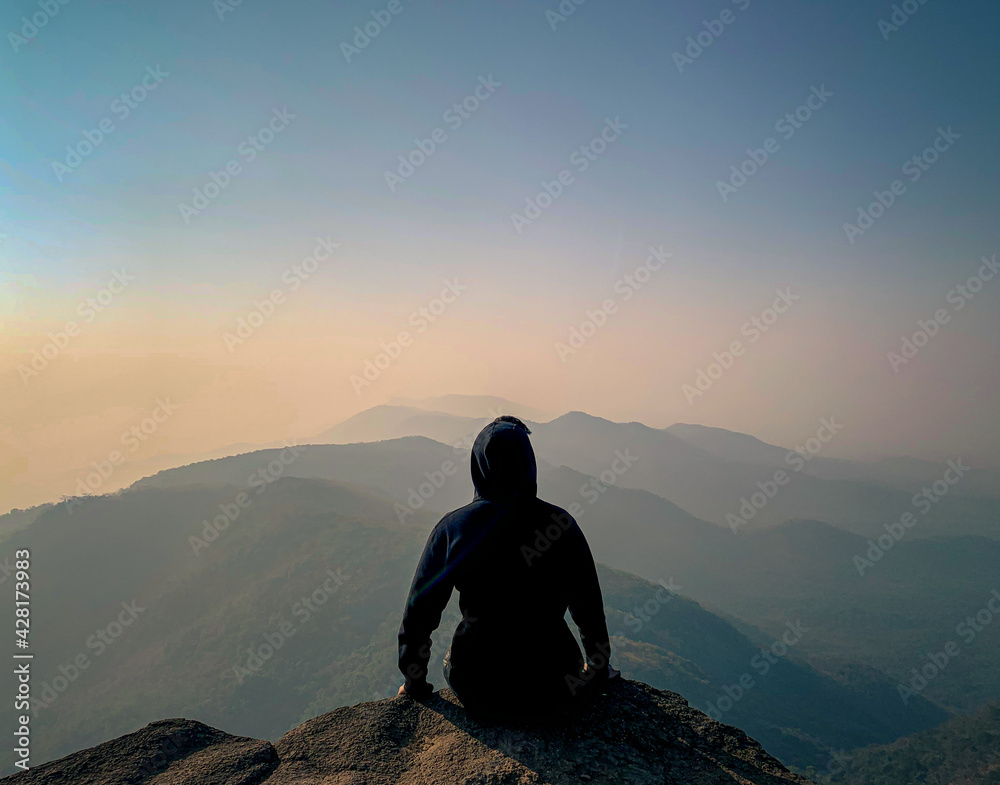 silhouette of person sitting on a top silhouette of person sitting on a top