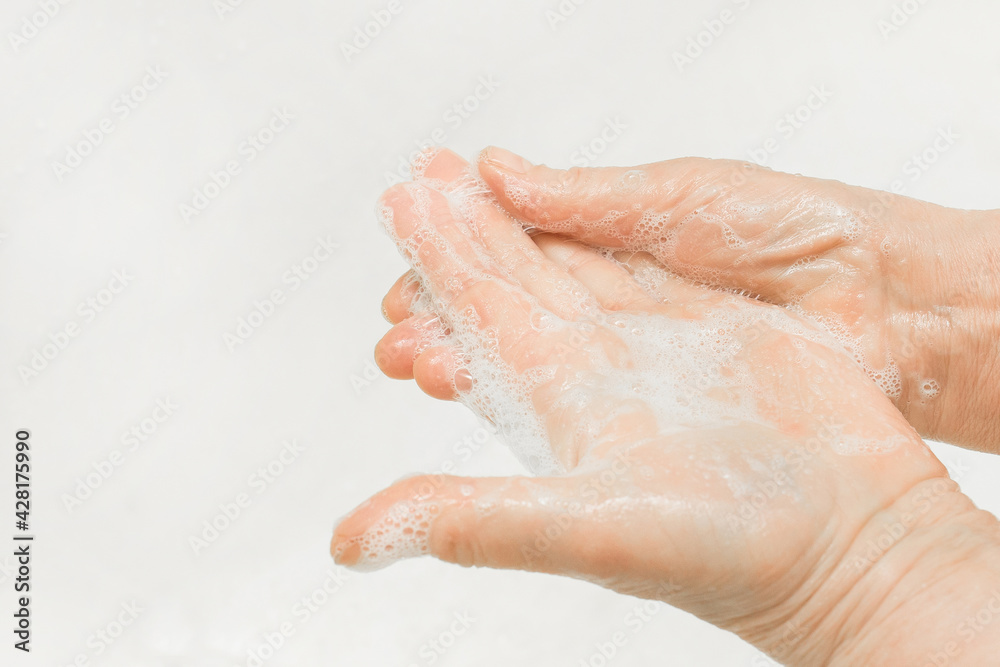 An adult woman's hands lathered with soap, close-up. Hand washing and domestic hygiene concept An adult woman's hands lathered with soap, close-up. Hand washing and domestic hygiene concept
