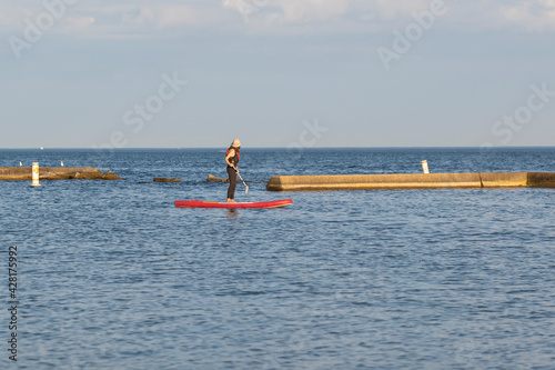 Photography Young fit teenage girl in a life vest paddle boarding on a stand up board  at Lake Ontario