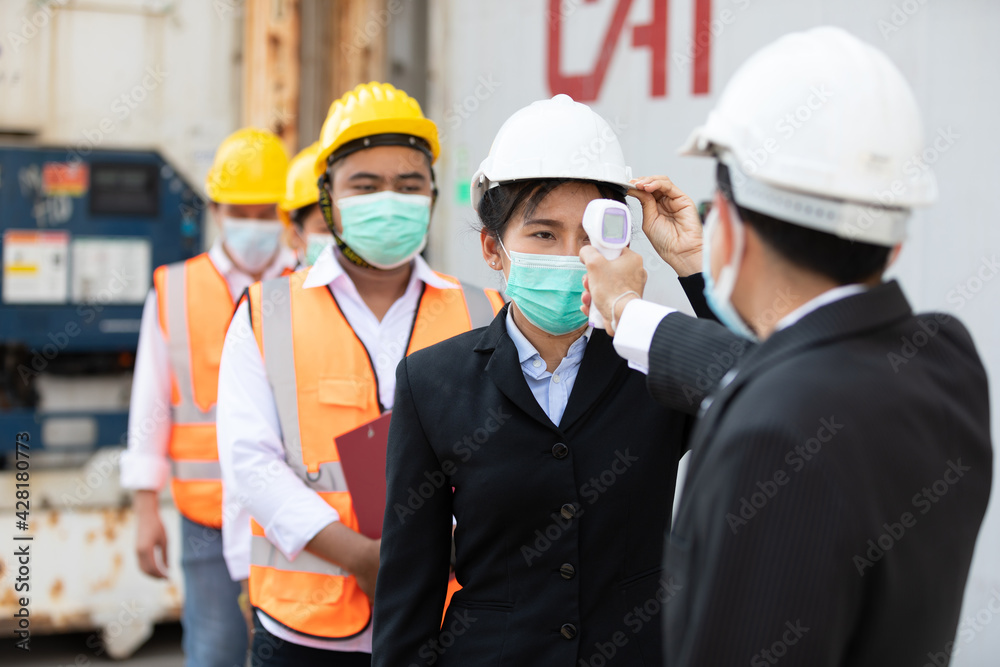 foreman scanning fever temperature with digital thermometer to workers in construction site foreman scanning fever temperature with digital thermometer to workers in construction site