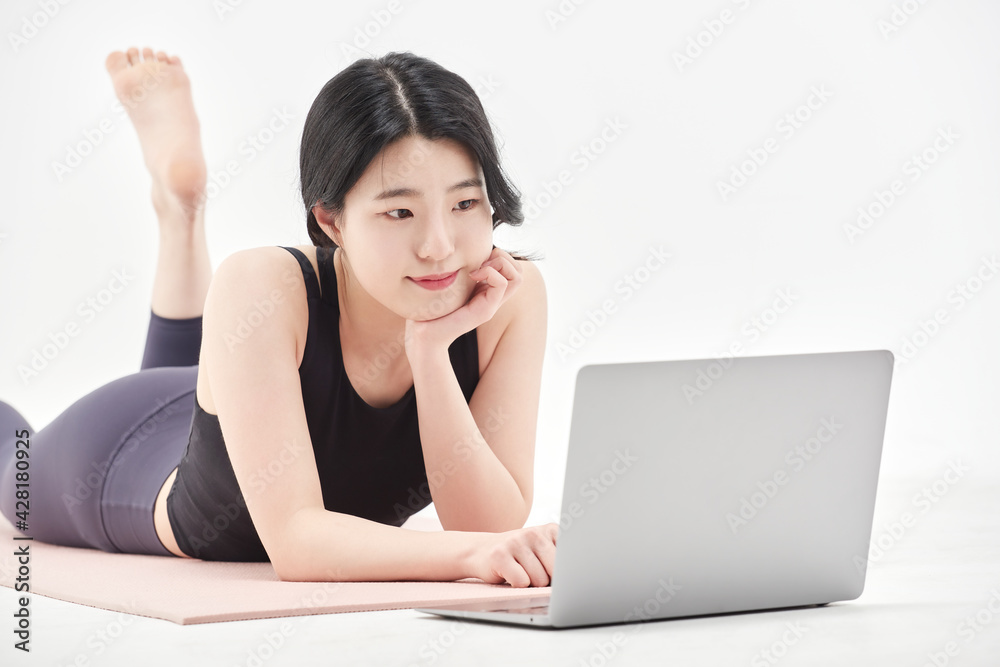 Asia korean girl long haired beautiful pilates or yoga athlete does a graceful pose while wearing a tight sports outfit against a white background in a studio Asia korean girl long haired beautiful pilates or yoga athlete does a graceful pose while wearing a tight sports outfit against a white background in a studio