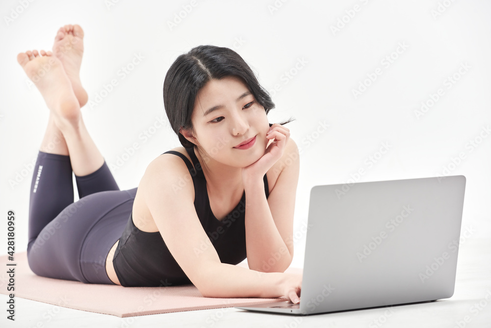 Asia korean girl long haired beautiful pilates or yoga athlete does a graceful pose while wearing a tight sports outfit against a white background in a studio Asia korean girl long haired beautiful pilates or yoga athlete does a graceful pose while wearing a tight sports outfit against a white background in a studio