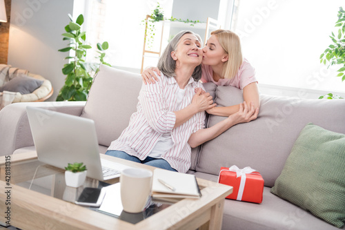 Photo of cheerful positive family daughter kiss mom good mood gift women day indoors inside house home