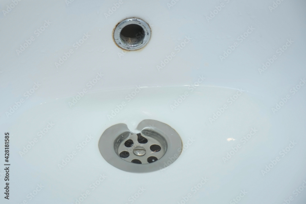 Water is draining in drain hole of the sink in bathroom, closeup view