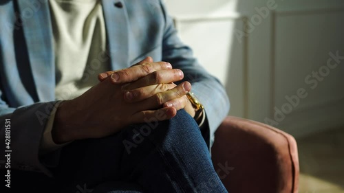 Businessman, project manager, head department sits red armchair blue suit, jeans with his fingers clasped his lap. Solves organizational issues, communication at meeting, conclusion of partner deal
