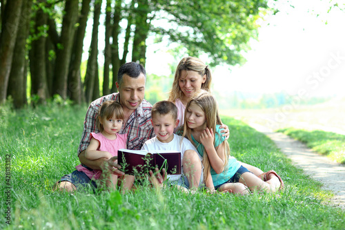 young family reading the Bible in nature