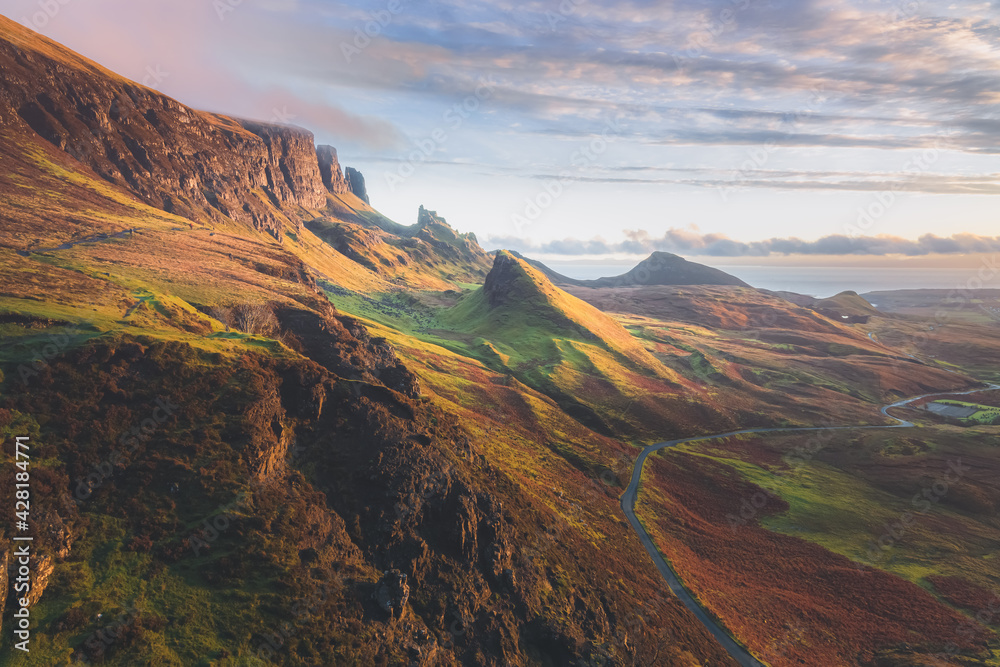 Golden light at sunset or sunrise over colourful landscape view of the rugged, otherworldly terrain of the Quiraing on the Isle of Skye, Scotland.