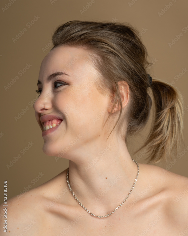 Smiling broadly girl with heterochromia, nose piercing and plug in one ear, and strange hairstyle