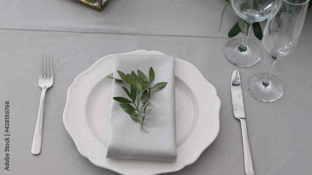 glasses, plates and utensils with napkins on the table in the white room. serving for the holiday. glasses, plates and utensils with napkins on the table in the white room. serving for the holiday.
