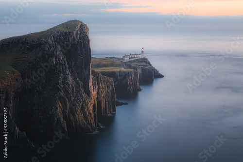 Photo Moody, atmospheric idyllic coastal seascape headland peninsula of Neist Point Lighthouse at sunset or sunrise on the Isle of Skye, Scotland