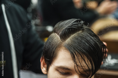 Hipster client man visiting in barber shop shaving hair. Modern guy having his hair cut in barbershop.