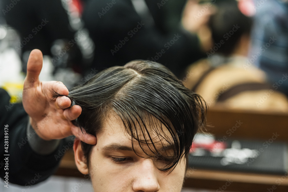 Naklejka premium Hipster client man visiting in barber shop shaving hair. Modern guy having his hair cut in barbershop.