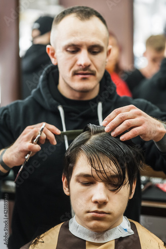 Hipster client man visiting in barber shop shaving hair. Modern guy having his hair cut in barbershop.