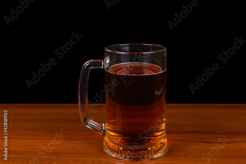 A mug of bad beer stands on a wooden surface.