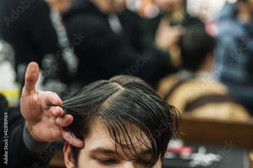 Hipster client man visiting in barber shop shaving hair. Modern guy having his hair cut in barbershop.