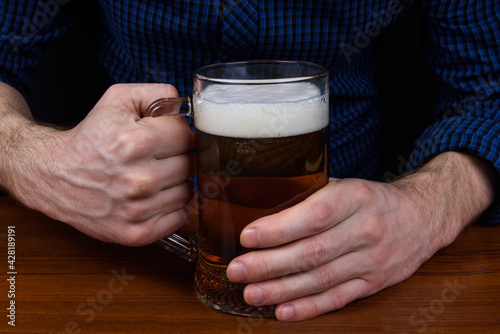 Mug with beer in the hands of a man