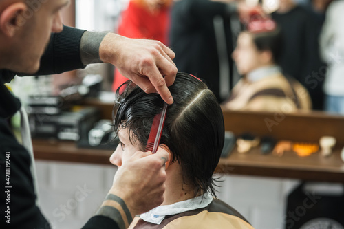 A man in a barbershop.Modern guy having his hair cut in barbershop