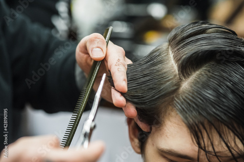 A man in a barbershop.Modern guy having his hair cut in barbershop © sharshonm