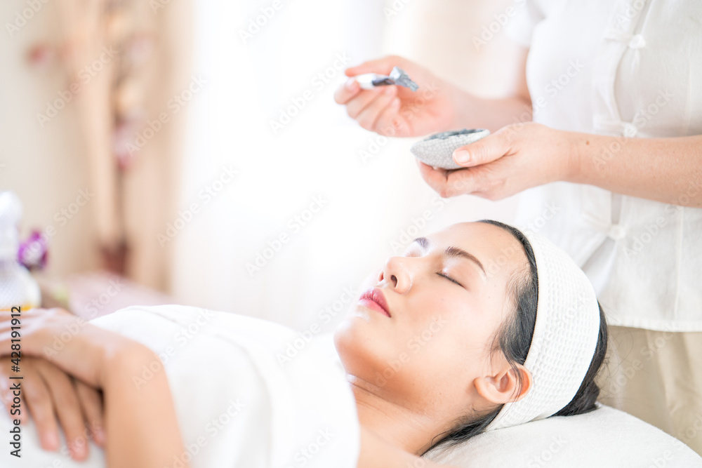 Face Skin Care. An Asian woman is masking her face in a spa salon. Woman with cosmetic spa facial mask. Face Skin Care. An Asian woman is masking her face in a spa salon. Woman with cosmetic spa facial mask.