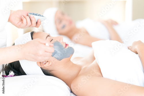 Face Skin Care. Young woman is masking her face in a spa salon.