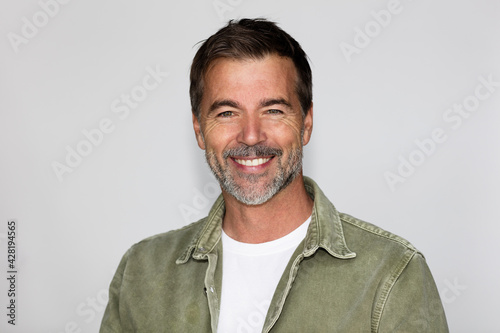 Handsome senior man smiling at the camera. He is confident and having sex appeal. Isolated on white