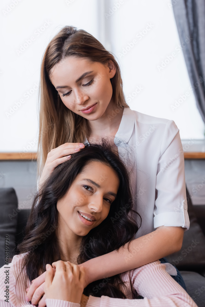 smiling lesbian woman embracing brunette girlfriend in living room smiling lesbian woman embracing brunette girlfriend in living room
