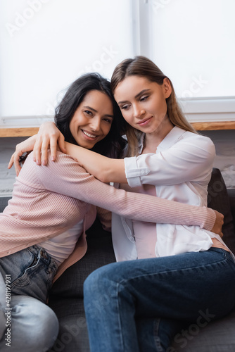 cheerful lesbian couple embracing each other in living room