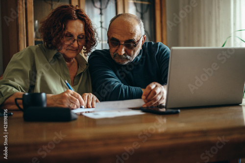 Senior couple doing finances while using a laptop at home