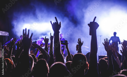 Silhouette of a man hands up in the air in a concert crowd