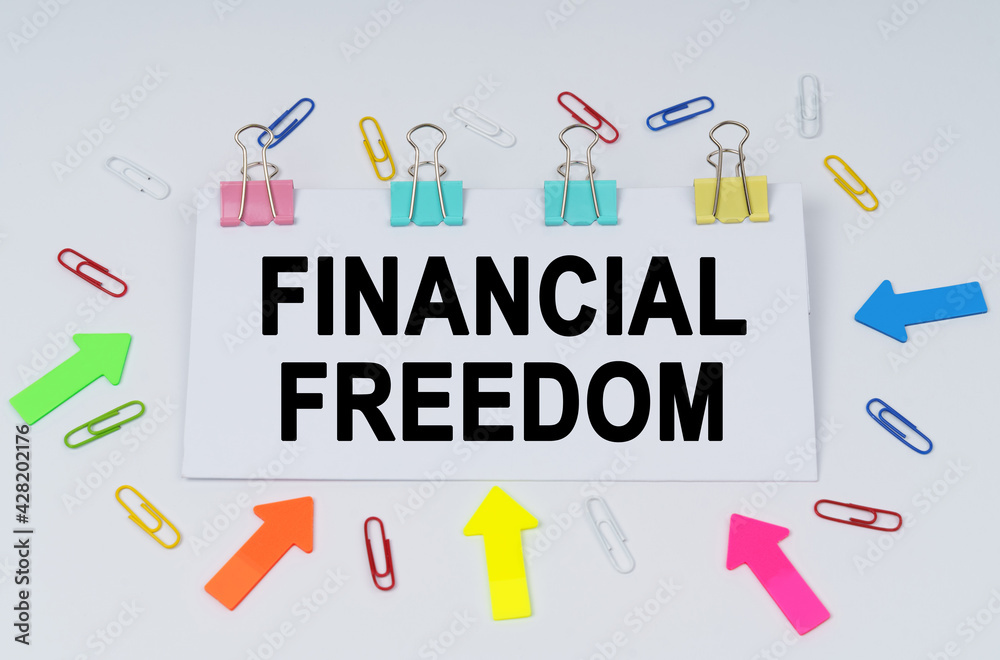 On the table there are paper clips and directional arrows, a sign that says - FINANCIAL FREEDOM On the table there are paper clips and directional arrows, a sign that says - FINANCIAL FREEDOM