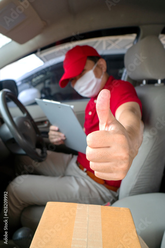 Delivery man employee in red cap t-shirt uniform mask checking preparing packages to deliver to customers who order online during the coronavirus or covid-19.