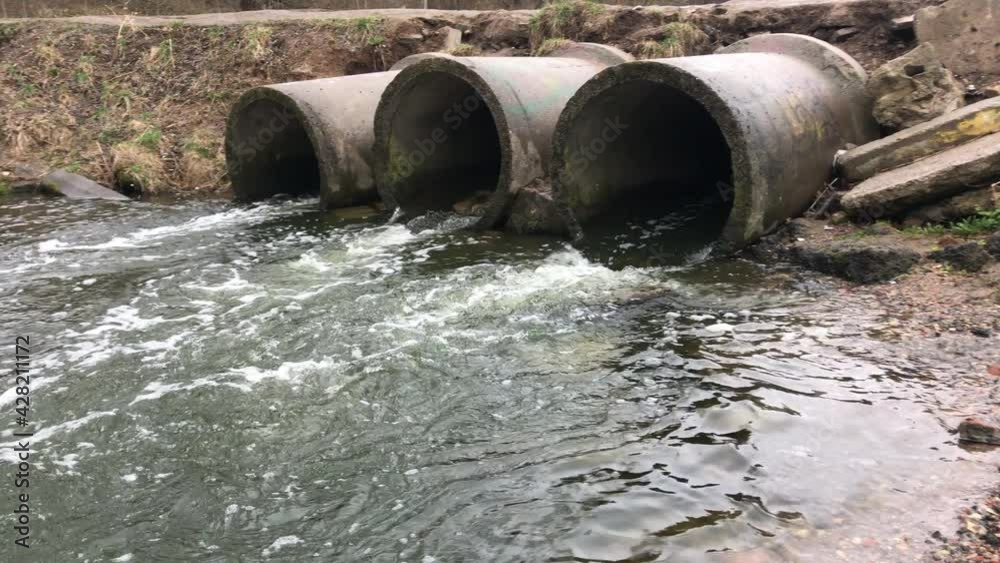 Streams of water flow through concrete sewers. Polluted body of water in the park Streams of water flow through concrete sewers. Polluted body of water in the park