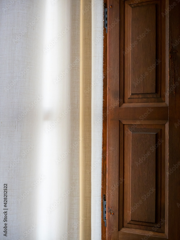 La luz penetra entre los visillos de una ventana de madera La luz penetra entre los visillos de una ventana de madera