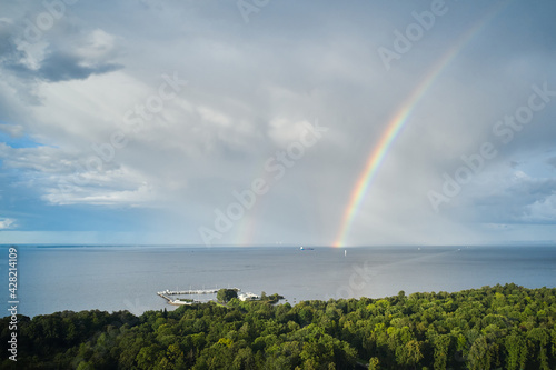 Aerial view of rainbow over sea and forest on a coastline