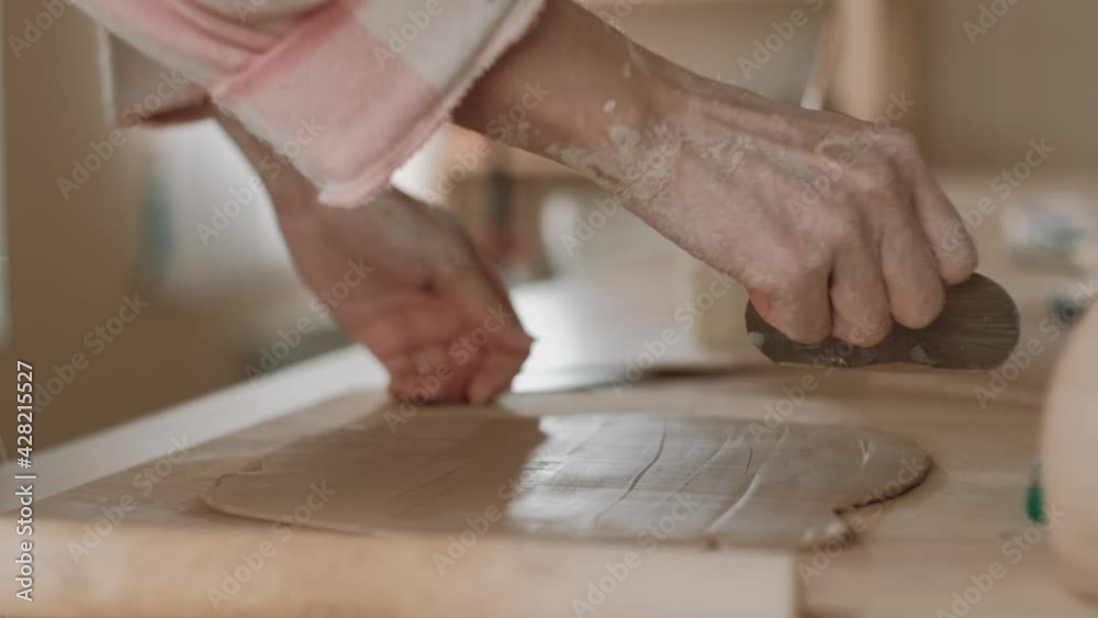 Handmade ceramic making. Woman artist smoothing clay on table using spatula, close up. Potter makes a clay product. Craft, handmade and creative skills. Handmade ceramic making. Woman artist smoothing clay on table using spatula, close up. Potter makes a clay product. Craft, handmade and creative skills.