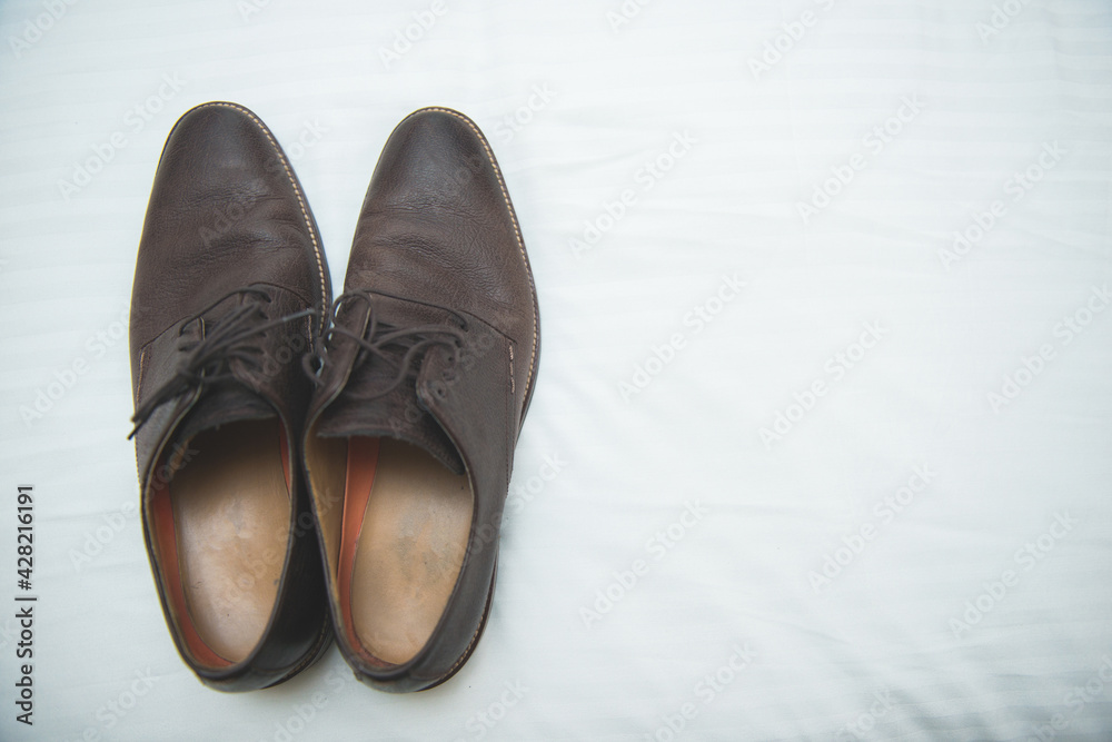 Pair of leather male formal shoes on a white surface - obrazy, fototapety, plakaty 