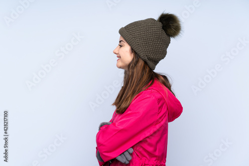 Young girl with winter hat isolated on blue background in lateral position