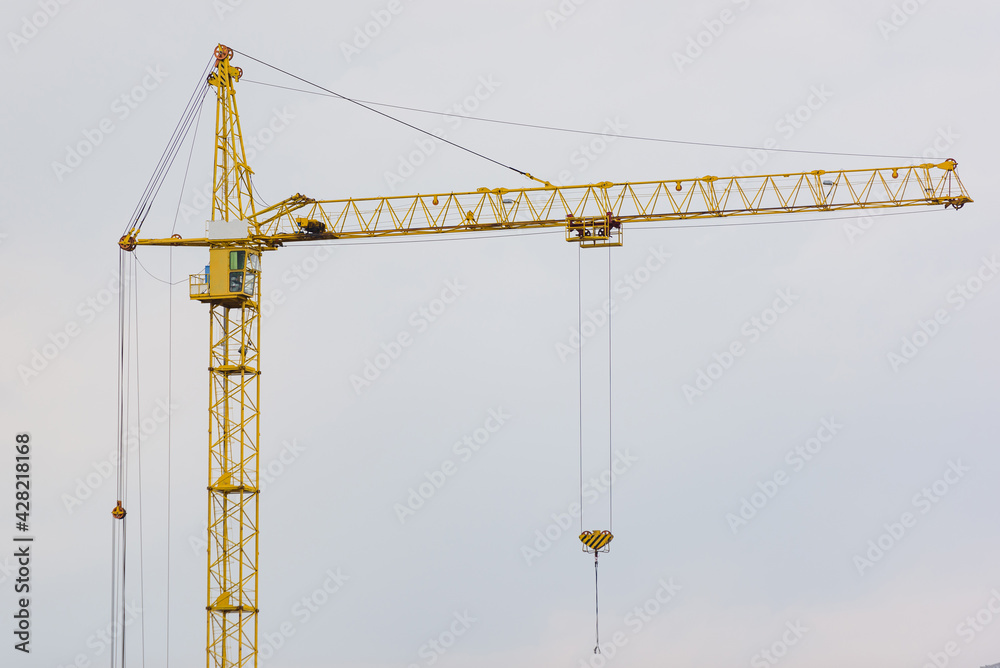 High-rise construction tower crane with a long yellow boom on the sky background High-rise construction tower crane with a long yellow boom on the sky background
