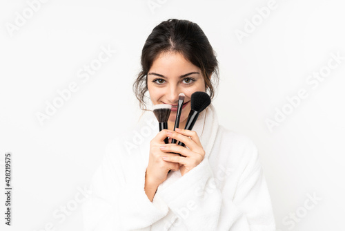 Young caucasian woman isolated on white background holding makeup brush and looking up