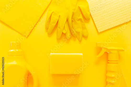 Yellow onochrome flat lay of cleaning tools. Colorful rubber gloves, spray, gel bottle, sponge, cloth photo