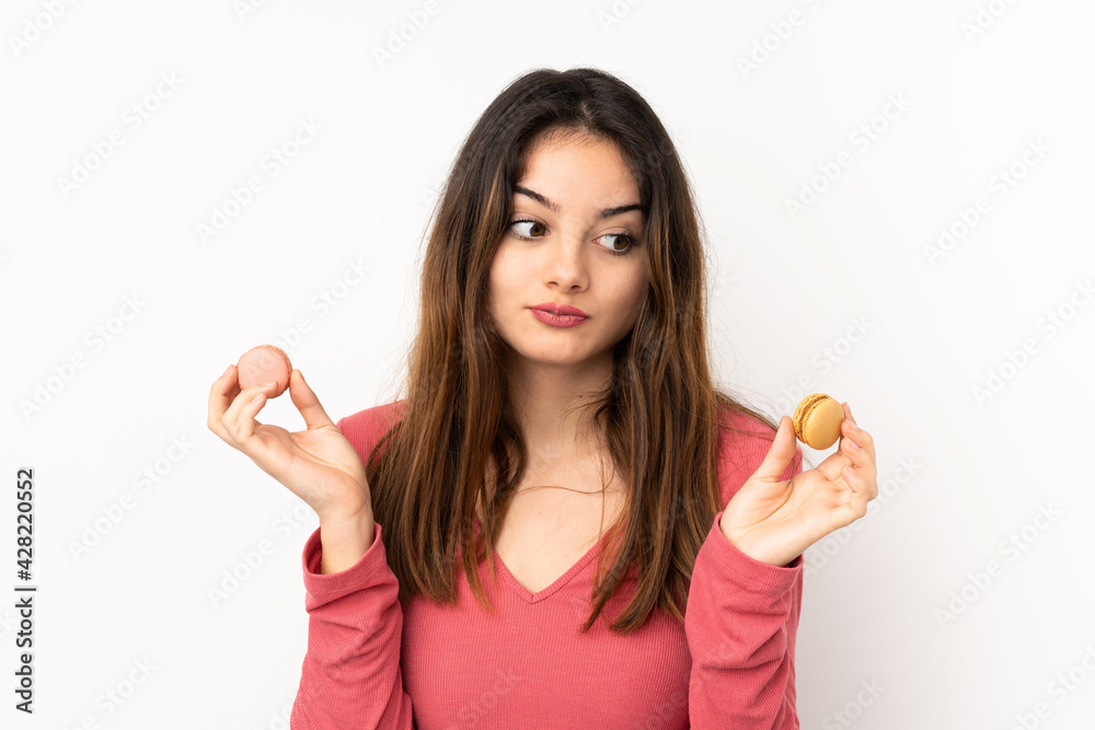 Young caucasian woman isolated on pink background holding colorful French macarons and unhappy Young caucasian woman isolated on pink background holding colorful French macarons and unhappy