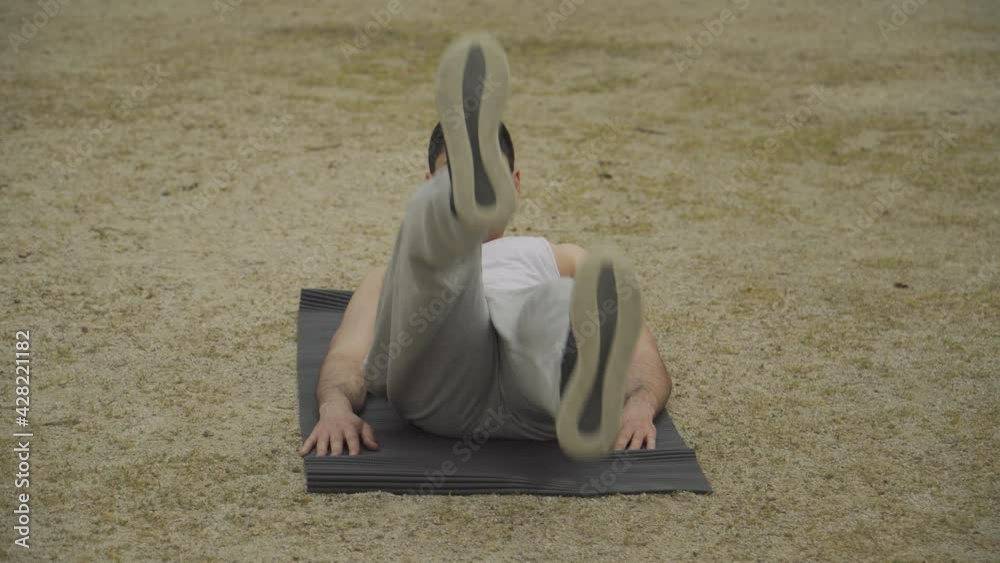 Hombre musculoso haciendo ejercicio abdominal estilo bicicleta, hombre en camiseta blanca sin mangas y chándal gris haciendo ejercicio, hombre de pelo corto entrenando en el parque, quemando grasa 
